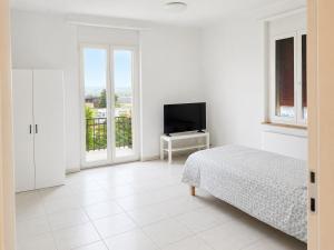 a white bedroom with a bed and a television at DreamWork Point Grenchen in Grenchen