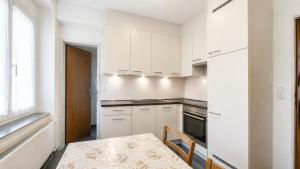 a kitchen with white cabinets and a table with chairs at DreamWork Point Grenchen in Grenchen