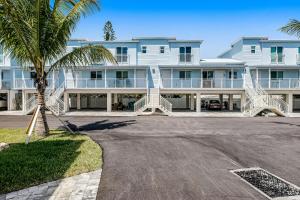 a large white building with a palm tree in front of it at Snowbird-friendly condo in oceanfront complex with heated pool, BBQ, AC in Marathon