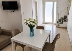 a vase of flowers on a white table in a living room at Dimora Azzurra in Pachino