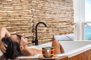a woman laying in a bath tub with a cup of coffee at ZAN Ocean View Hotel in Jambiani