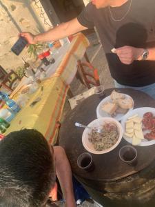 Eine Gruppe von Menschen sitzt an einem Tisch mit einem Teller Essen in der Unterkunft Il Muraglio in Belmonte Calabro
