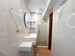 a white bathroom with a sink and a mirror at Haus Niko Apartments and Suites in Nea Potidaea +62 photos