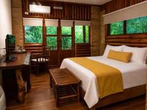 a bedroom with a bed and a desk and windows at La Aldea De La Selva Lodge in Puerto Iguazú +65 photos
