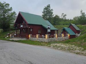 a red barn with a green roof next to a road at Guest house Anka in Žabljak