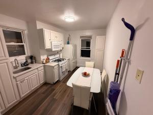a kitchen with white cabinets and a table and a refrigerator at Spacious 2BR Getaway Easy Access to NYC & Newark in Kearny