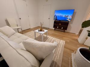 a living room with a white couch and a tv at Spacious 2BR Getaway Easy Access to NYC & Newark in Kearny