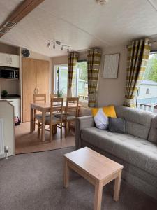 a living room with a couch and a table at 10 the green lilliardsedge carvan park harritsfield jedbrugh td8 6tz in Harrietsfield