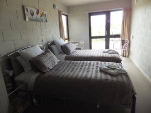 a bedroom with two beds and a window at Waitomo Golfstays B&B in Otorohanga