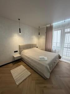 a white bedroom with a large bed with two towels on it at Поляна Апарт in Polyana