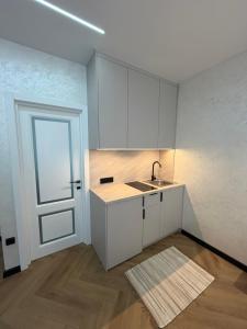 a kitchen with white cabinets and a sink and a door at Поляна Апарт in Polyana