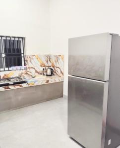 a stainless steel refrigerator in a kitchen with a counter at Paragone Home Stay Modern 3BR Apartment Style Home AC 5 Min to Enderamulla Station 15 Minute Train Ride to Colombo in Wattala