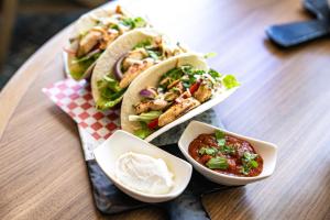 a table with three tacos and a bowl of dips at Hyatt Place Bayamon in Bayamón +77 photos