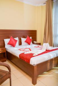a bedroom with a bed with red pillows on it at Delfirm Hotel in Nairobi