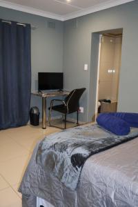 a bedroom with a bed and a desk with a computer at MERK Guest House in Piet Retief