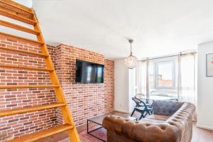 a living room with a brick wall and a couch at Rockefeller - Le petit Loft New-Yorkais 5 Min de la plage in Dunkerque