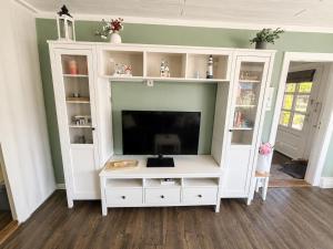 a white entertainment center with a flat screen tv at Lütte Butze in Marne