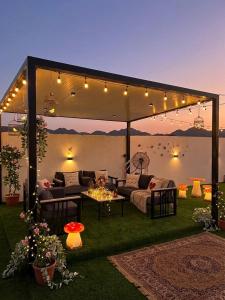 a patio with a couch and a table and lights at شاليه غرام حتا - Hatta Romance Chalet in Būbādī