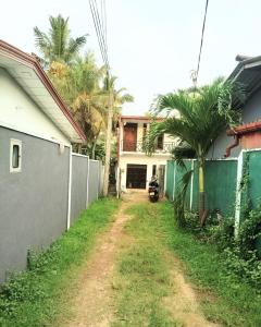 a dirt road in front of a house with palm trees at Paragone Home Stay Modern 3BR Apartment Style Home AC 5 Min to Enderamulla Station 15 Minute Train Ride to Colombo in Wattala