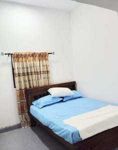a bed with blue sheets and pillows in a room at Paragone Home Stay Modern 3BR Apartment Style Home AC 5 Min to Enderamulla Station 15 Minute Train Ride to Colombo in Wattala