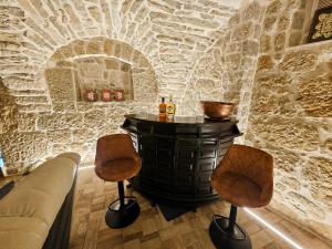 a bar in a stone walled room with two stools at Adria Stone House in Grižane