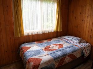 a bed in a wooden room with a window at El Urco Chiloé - Cabaña Guapilacuy in Ancud
