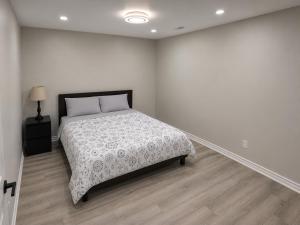a white bedroom with a bed and a lamp at Newly Renovated 2BR Walkout Suite in the Heart of Kanata Ottawa in Ottawa