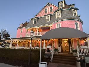 a large pink house with an umbrella in front of it at The Grenville Hotel and Restaurant in Bay Head