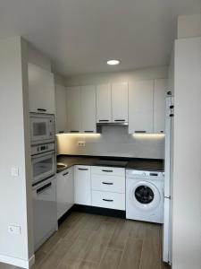 a kitchen with white cabinets and a washing machine at Apartamento Mediodía 3 in La Bañeza