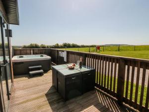 a deck with a hot tub and a table on a deck at Willow Lodge in Whitby