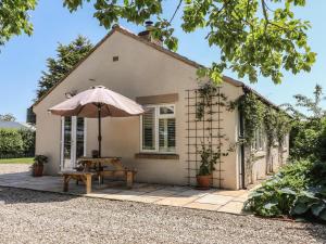 a small house with an umbrella and a table at Low Grounds Cottage in York