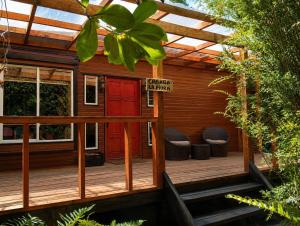 a cabin with a red door and stools on a deck at El Urco Chiloé - Cabaña La Fiura in Ancud