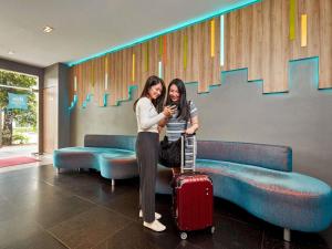 two women standing next to each other with a suitcase at ibis budget Singapore Bugis in Singapore