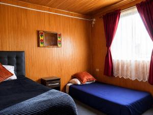 a bedroom with two beds and a window at El Urco Chiloé - Hostal y Cabaña in Ancud