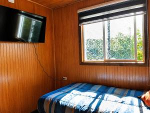 a bedroom with a bed and a flat screen tv at El Urco Chiloé - Hostal y Cabaña in Ancud