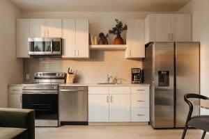 a kitchen with white cabinets and a stainless steel refrigerator at Ceros in Denver