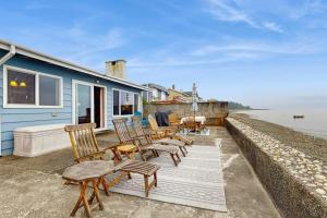 a group of chairs and tables on a deck next to a house at Oceanfront Beauty in Blaine