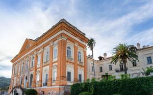 a large building with palm trees in front of it at Grotta Cimabue in Caserta