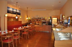 a restaurant with tables and chairs and a kitchen at Hiddenseer Hotel in Stralsund
