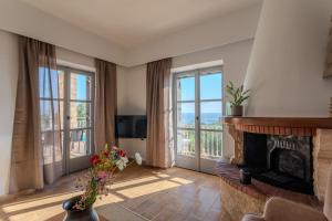 a living room with a fireplace and large windows at Aether Blue Eco Villas in Agios Nikolaos