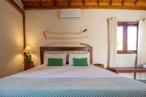 a bedroom with a large bed with two green pillows at Casa Caroá - Chalé 2 in Japaratinga