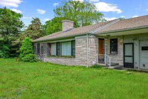 a small house with a grass yard at Relaxing Barnstable Getaway Close to the Beach in Barnstable