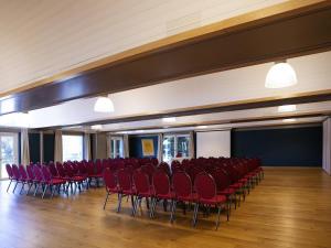 an empty room with red chairs and a stage at ibis Styles Lille Neuville en Ferrain in Neuville-en-Ferrain +50 photos