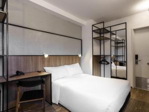a bedroom with a white bed and a desk at ibis Botucatu in Botucatu +74 photos