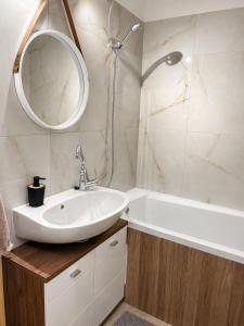 a bathroom with a sink and a mirror and a tub at Harmónia Home in Miskolc