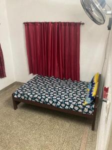 a bed in a room with a red curtain at sree thilak apartments in Guruvāyūr