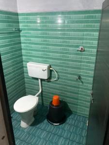 a green tiled bathroom with a toilet in a stall at sree thilak apartments in Guruvāyūr