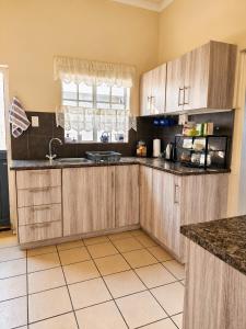 a kitchen with wooden cabinets and a tile floor at The Big Tree Cottage in Graafwater