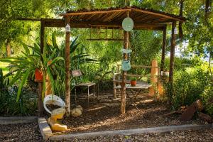 a wooden gazebo with a bench and a chair at The Big Tree Cottage in Graafwater