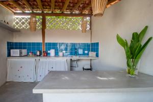 a kitchen with a white counter and blue tiles at Casa Caroá - Chalé 2 in Japaratinga +71 photos